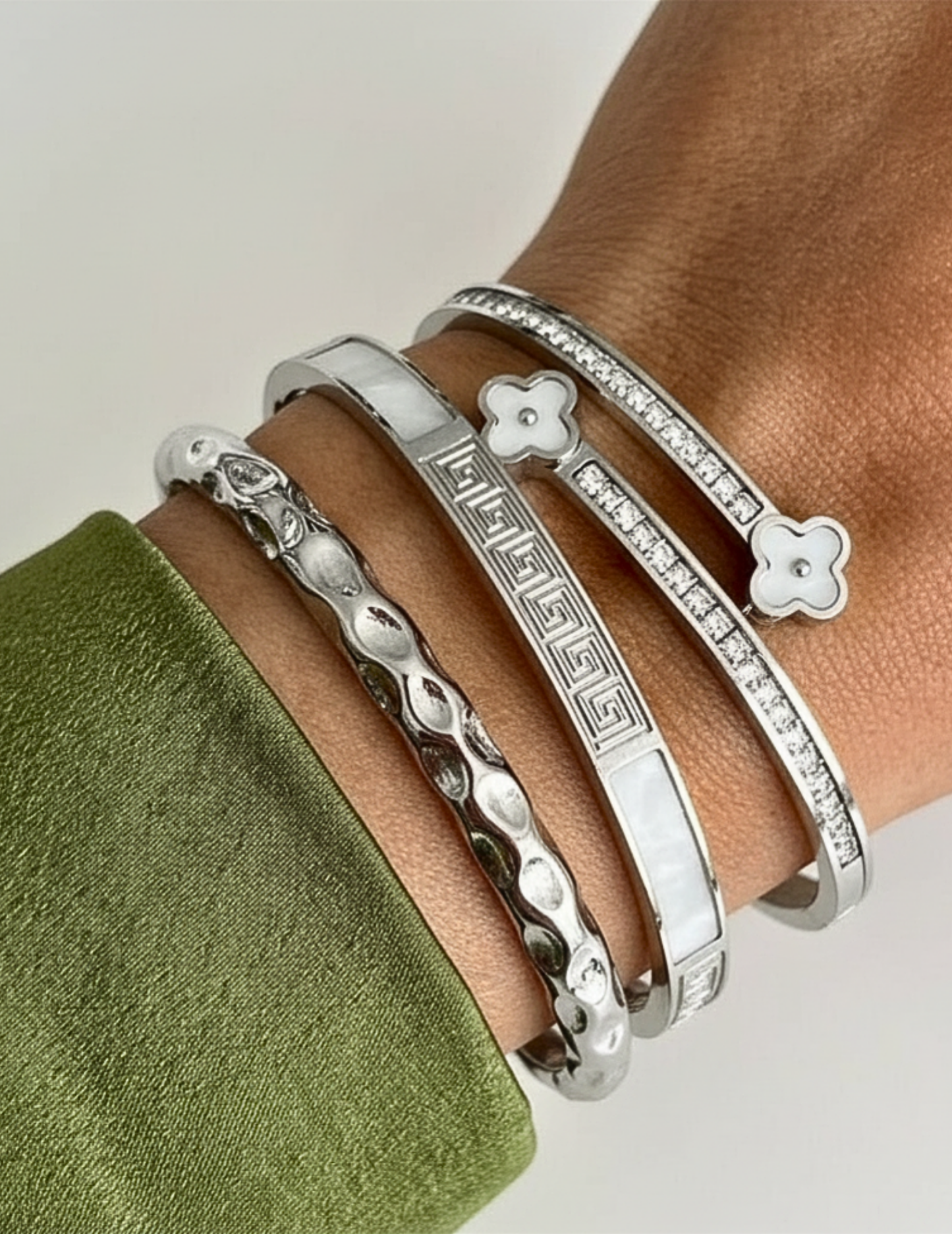 Silver bracelets on a wrist with a neutral background