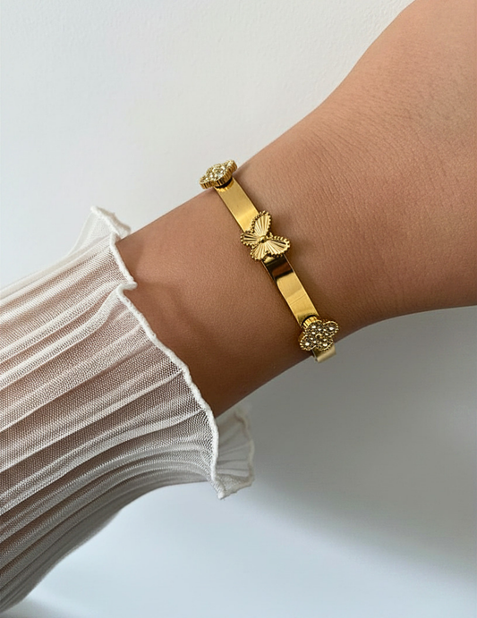 wrist wearing gold bracelet on neutral background