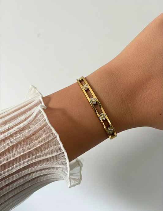 wrist wearing gold floral bangle on neutral background