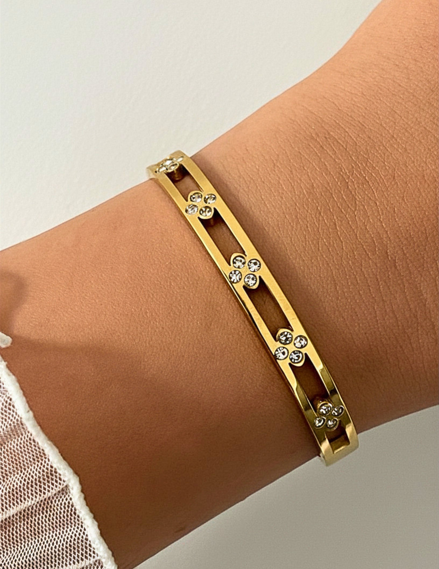 wrist wearing gold floral bangle on neutral background