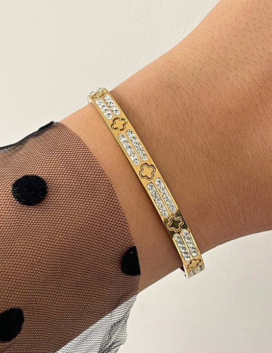 WRIST WEARNG GOLD BANGLE ON NEUTRAL BACKGROUND