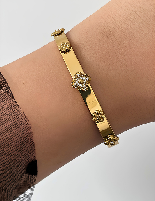 WRIST WEARNG GOLD BANGLE ON NEUTRAL BACKGROUND