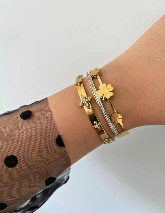 WRIST WEARNG TWO GOLD BANGLE ON NEUTRAL BACKGROUND