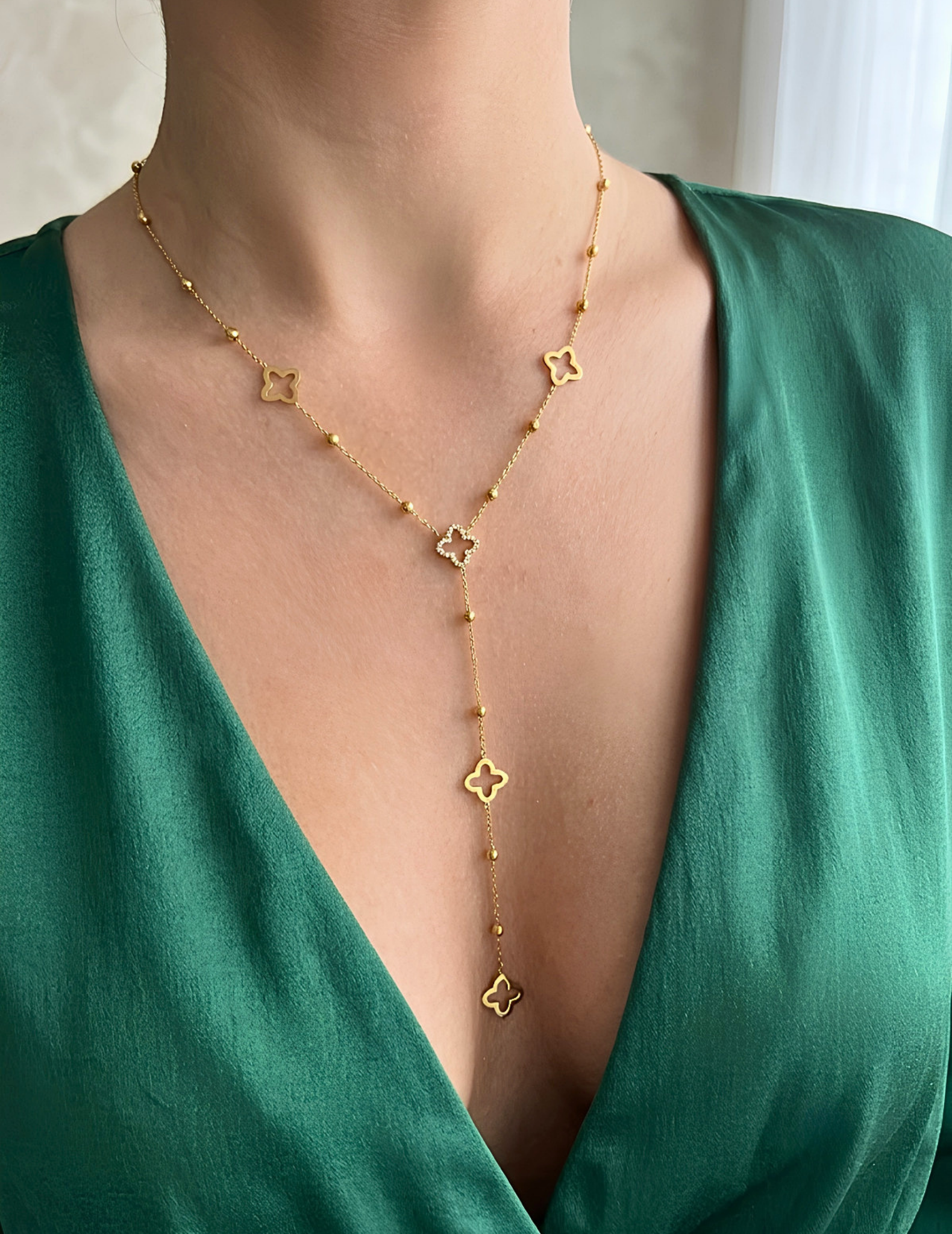 WOMAN WEARING GOLD PLATED CLOVER NECKLACE WEARING GREEN SHIRT
