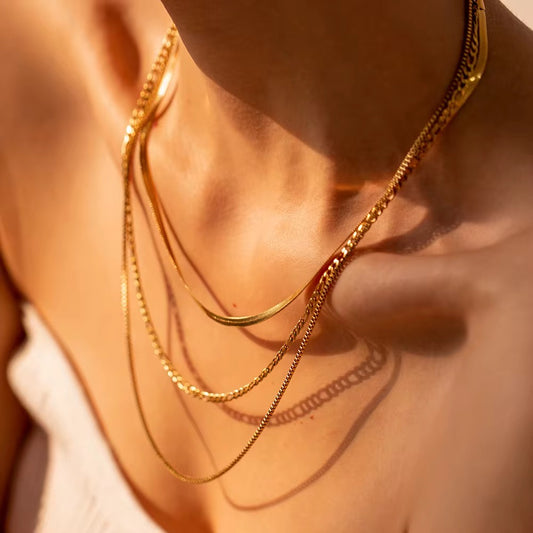 Close-up of a person wearing multiple gold necklaces on a blurred background