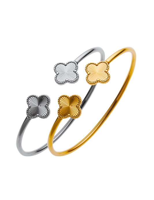 a gold plated and a silver clover bangles on white background
