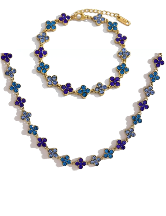 Gold necklace and bracelet with blue and floral beads on a white background
