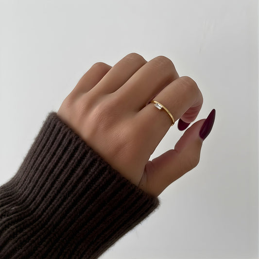 Hand wearing a gold ring with a plain background