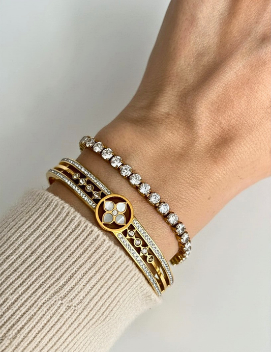 Gold bracelets on a wrist with a neutral background