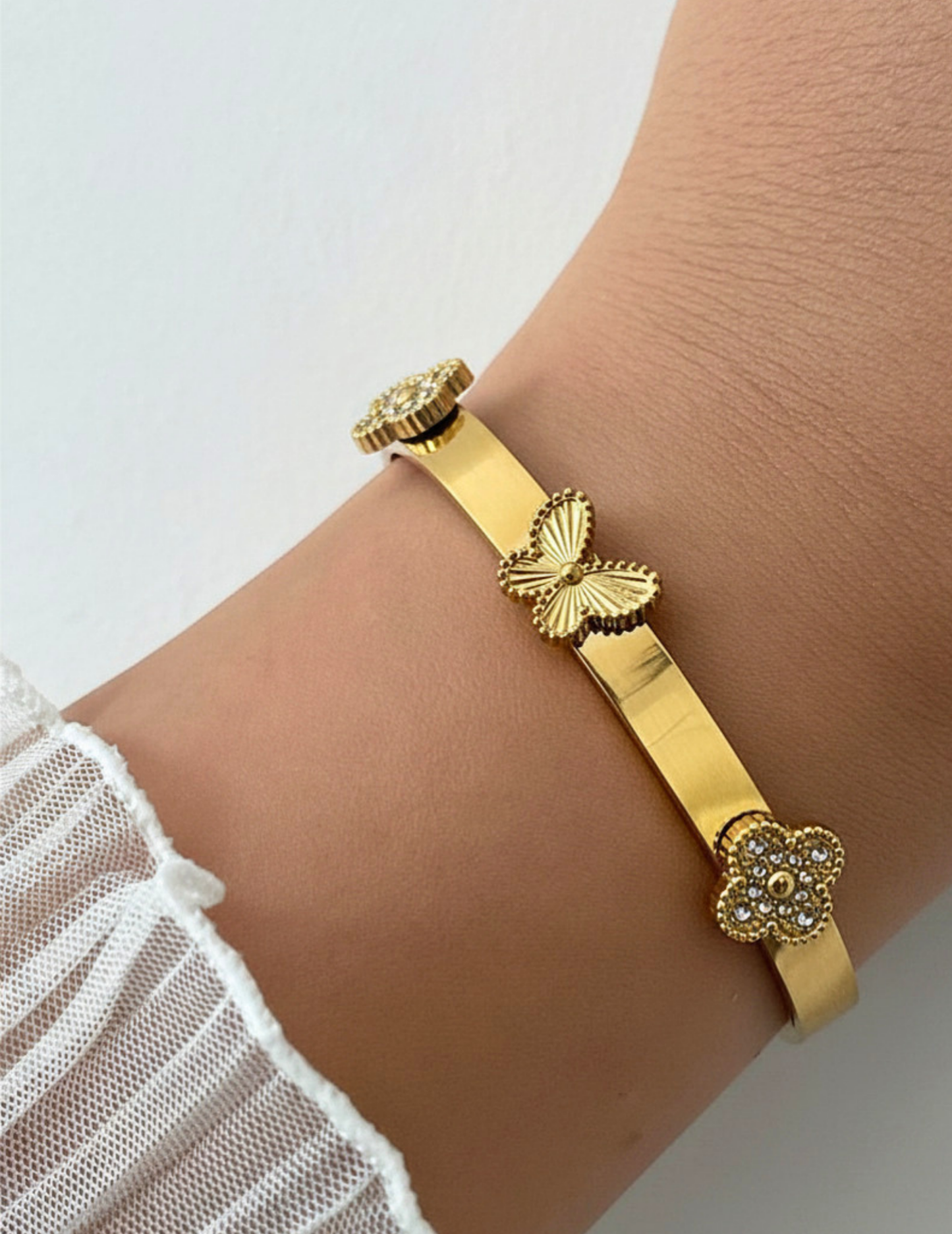wrist wearing gold bracelet on neutral background