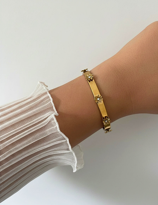 wrist wearing gold bangle on neutral background