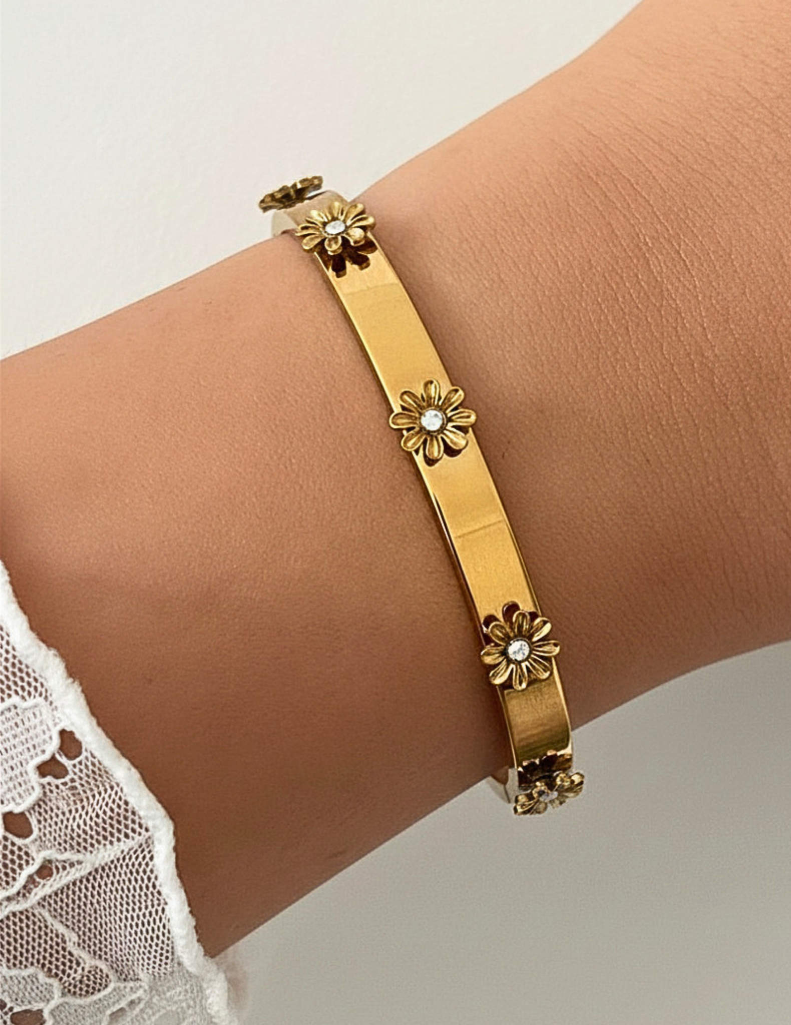 wrist wearing gold bangle on neutral background