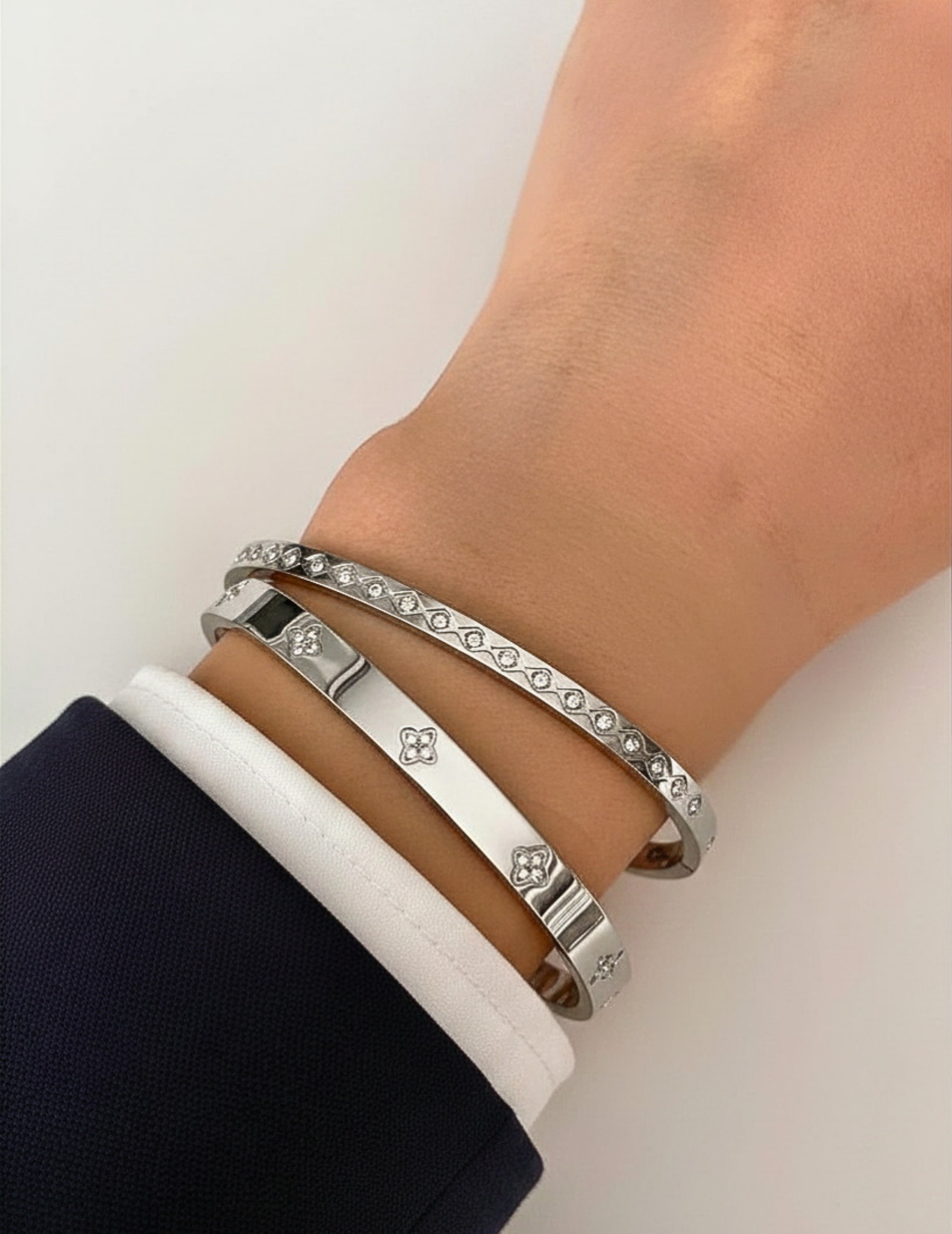 wrist wearing silver bangles on neutral background