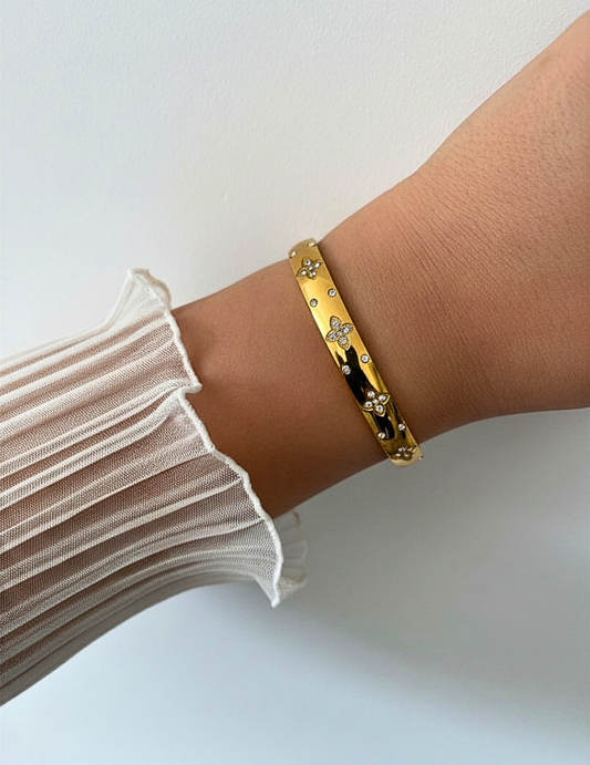 wrist wearing gold bangle on neutral background