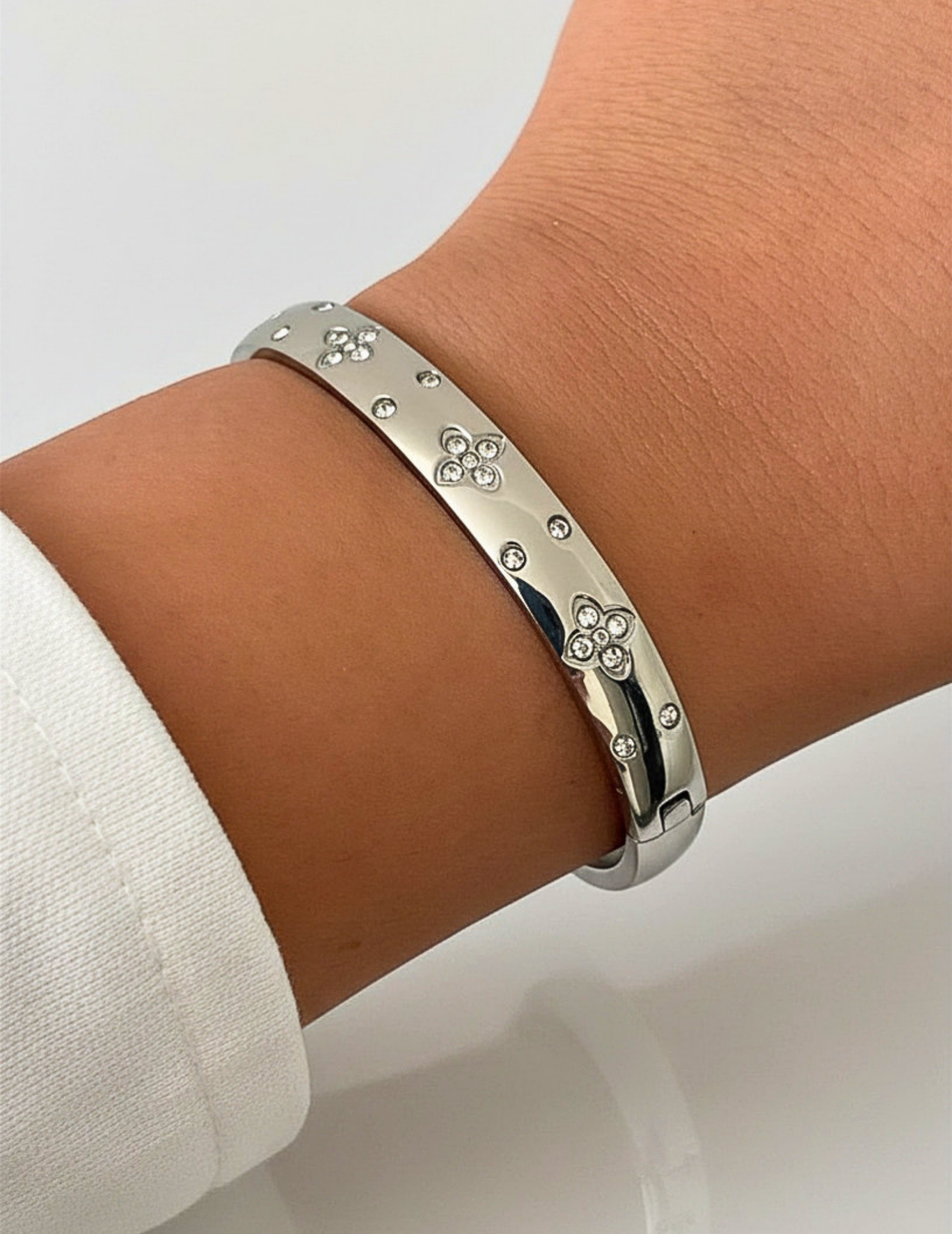 wrist wearing silver bangle on neutral background