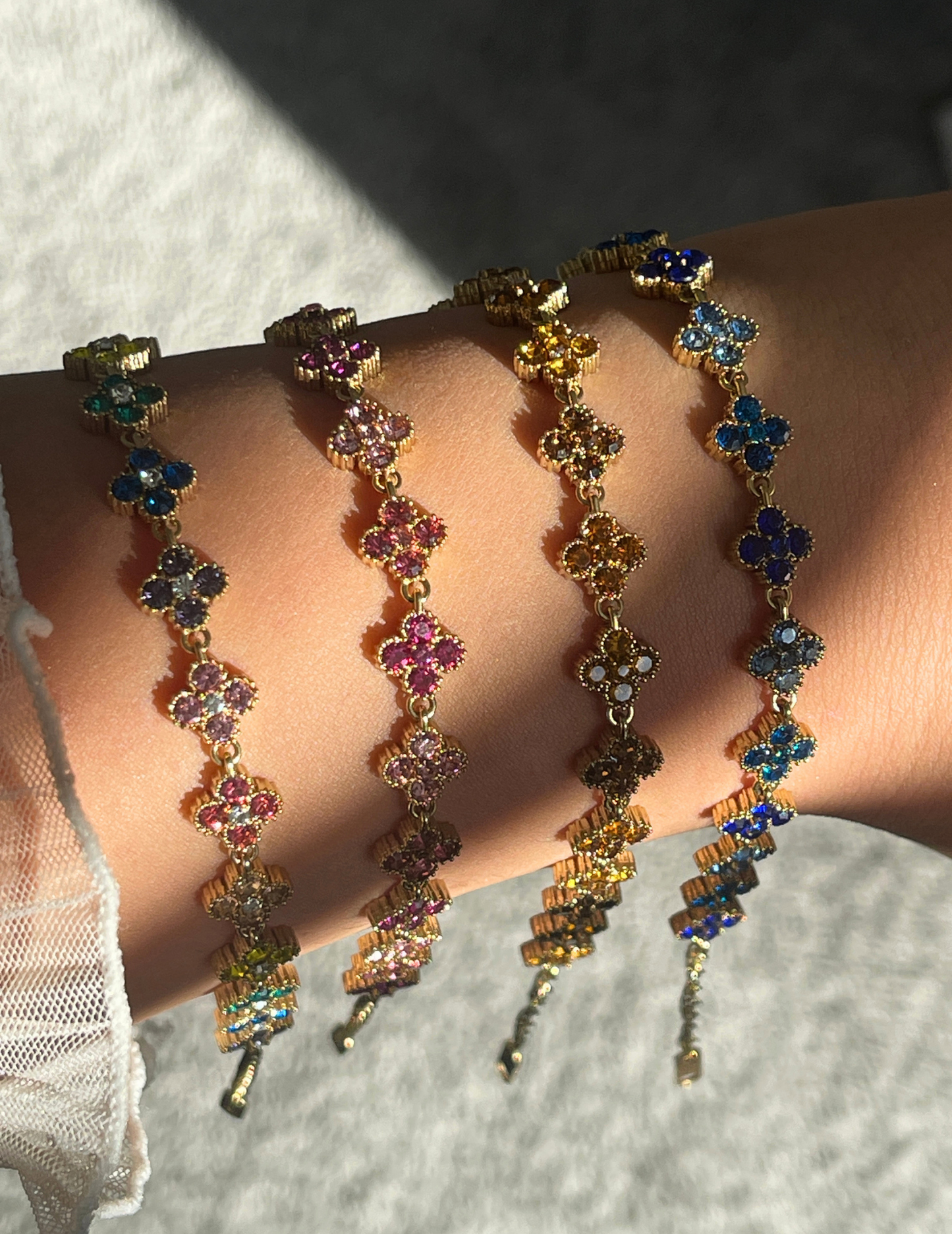 wrist wearing four colorful clover bracelets on neutral background