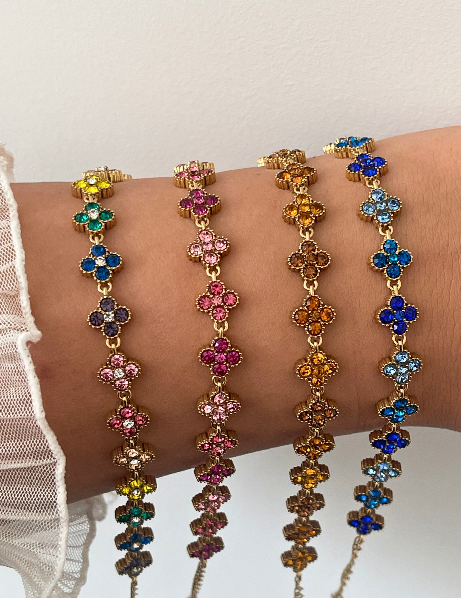 wrist wearing four colorful clover bracelets on neutral background