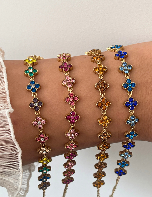 wrist wearing four colorful clover bracelets on neutral background