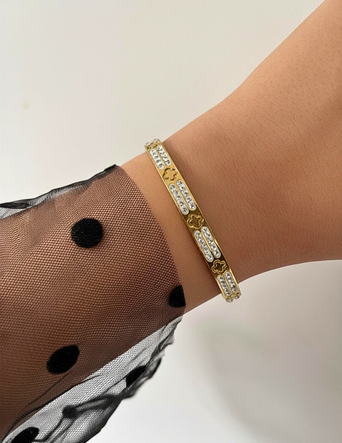 WRIST WEARNG GOLD BANGLE ON NEUTRAL BACKGROUND