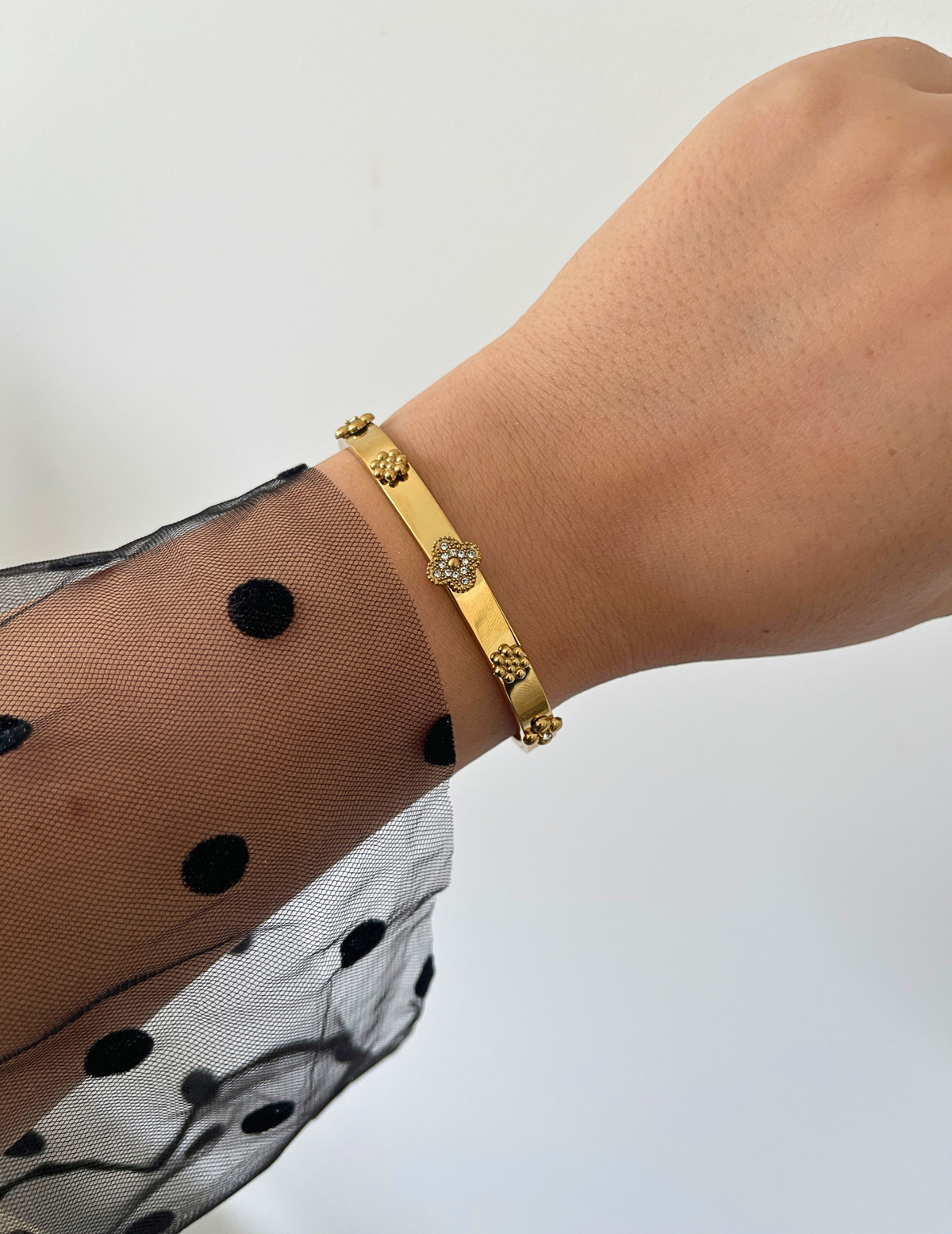 WRIST WEARNG GOLD BANGLE ON NEUTRAL BACKGROUND