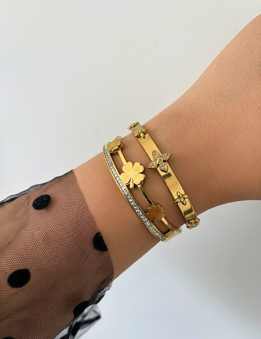 WRIST WEARNG TWO GOLD BANGLE ON NEUTRAL BACKGROUND
