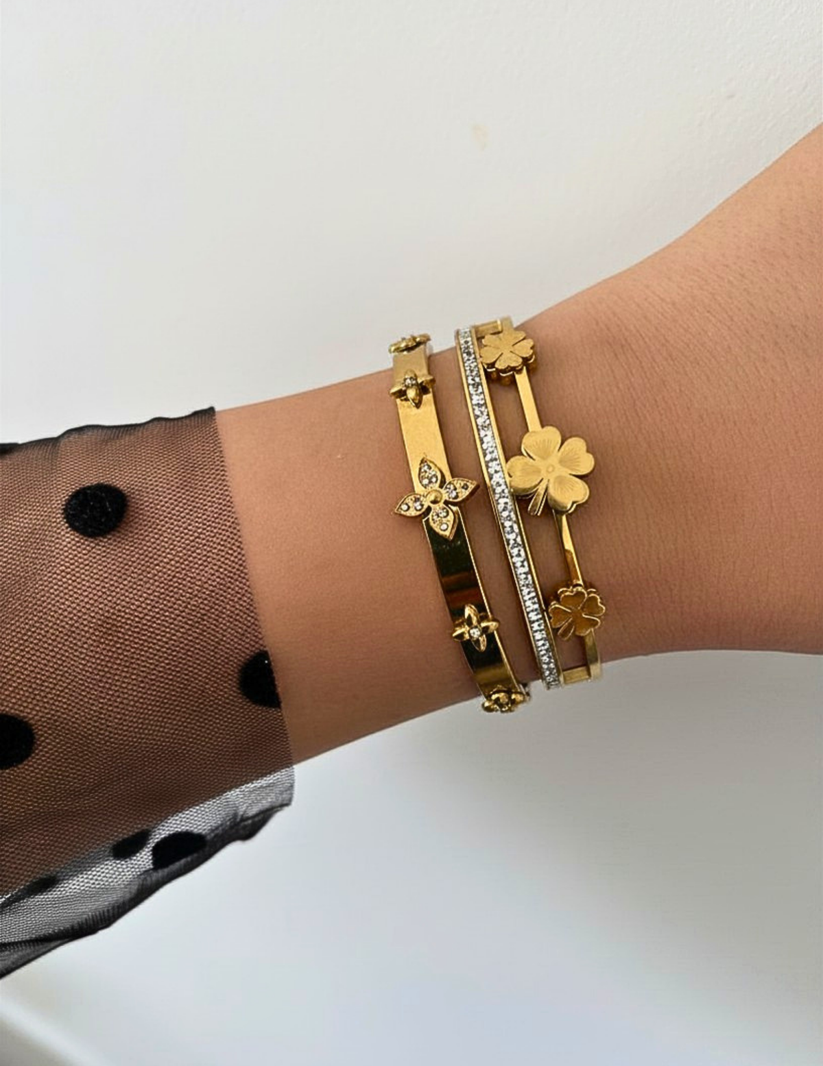 WRIST WEARNG TWO GOLD BANGLE ON NEUTRAL BACKGROUND