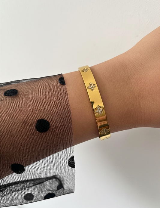 WRIST WEARNG GOLD BANGLE ON NEUTRAL BACKGROUND