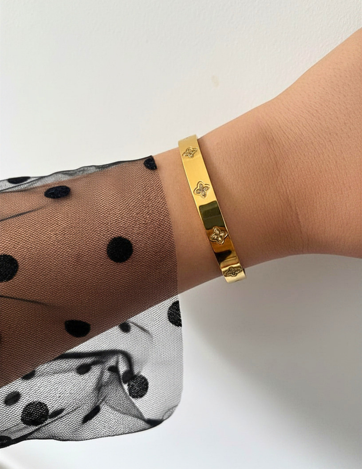 WRIST WEARNG GOLD BANGLE ON NEUTRAL BACKGROUND