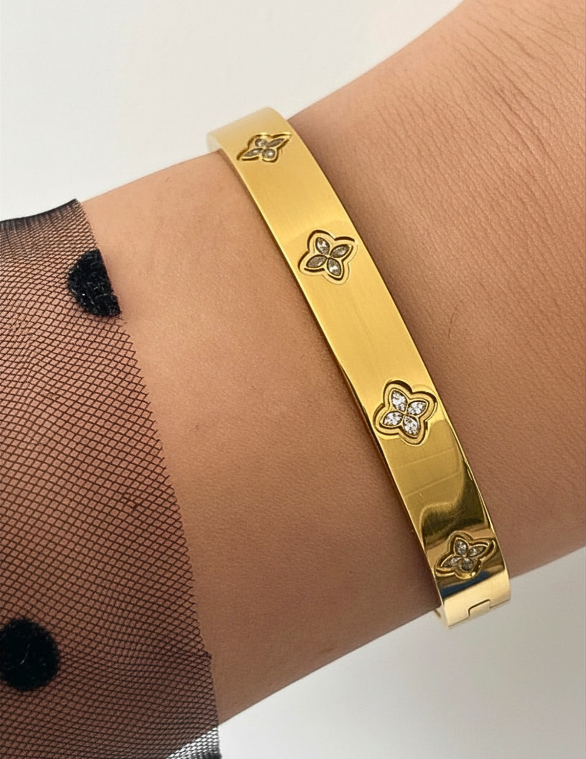 WRIST WEARNG GOLD BANGLE ON NEUTRAL BACKGROUND