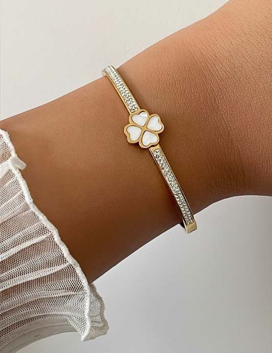 hand wearing gold plated bangle laying on white plain surface