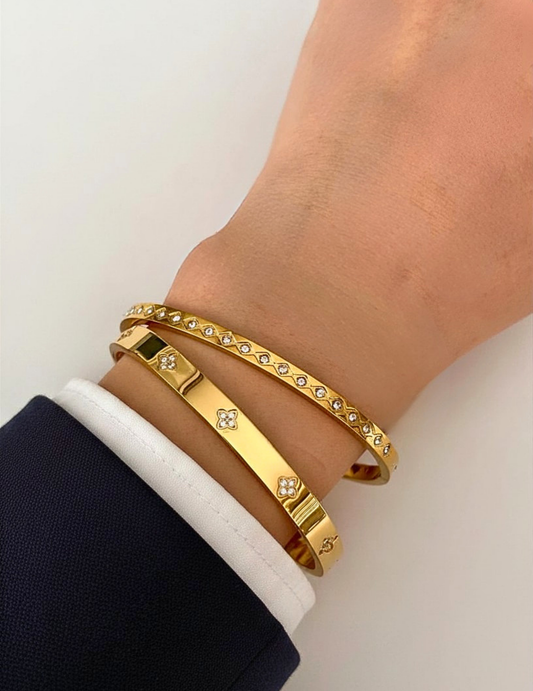 wrist wearing gold bangles on neutral background
